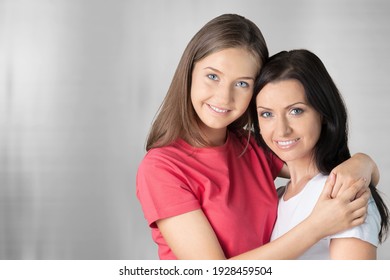 Happy portrait loving daughter hugging mother from back, looking at camera, posing for family photo
