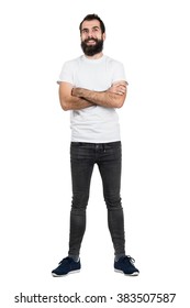 Happy Positive Bearded Hipster In White T-shirt And Tight Jeans With Crossed Arms. Full Body Length Portrait Isolated Over White Studio Background. 