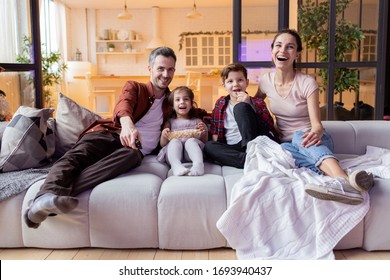 Happy Positive Family With Kid Enjoy Movie Time On TV. Overjoyed Parent And Children Watching Funny Tv-show Program On Television Eating Popcorn Snack And Laughing Loudly. Weekend, Evening At Home