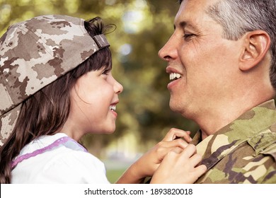 Happy Positive Father Holding Little Daughter In Arms, Hugging Girl And Talking To Her Outdoors After Returning From Military Mission Trip. Closeup Shot. Family Reunion Or Returning Home Concept