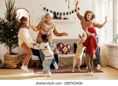 Happy Positive Multiracial Family With Three Kids And Golden Retriever Have Fun On Christmas Day At Home. Mother, Grandmother And Multiethnic Children Dance To New Year Music During Winter Holidays