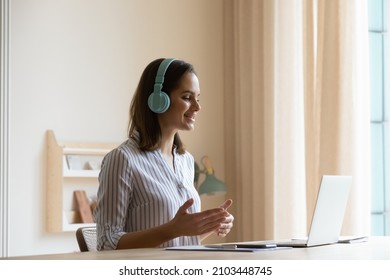 Happy positive online teacher, coach in big wireless headphones speaking at laptop webcam, giving webinar, virtual training, explaining class. Student attending remote lesson, making video call