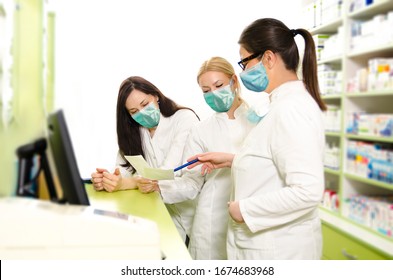 Happy positive pharmacists with surgical masks on face organizing theirs work day 