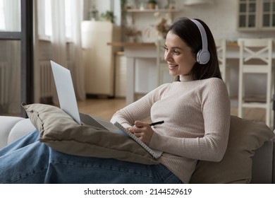 Happy Positive Young Student Woman In Wireless Headset Watching Online Lesson On Laptop, Studying Foreign Language, Attending Virtual Class, Webinar, Talking On Video Call To Teacher, Resting On Couch