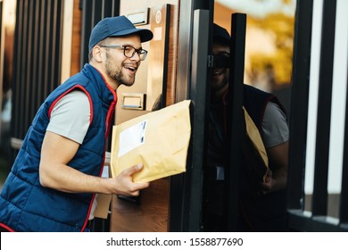 Happy Postal Worker Delivering Package To His Customer And Ringing On Intercom At Front Gate.