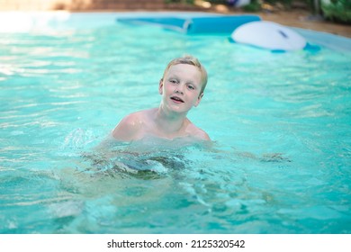 Happy Pre Teen Boy Swimming In Backyard Pool