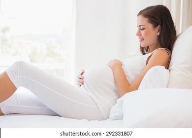 Happy Pregnancy Sitting On Sofa At Home In Bedroom