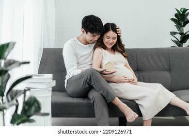 Happy Pregnant Asian Couple. Together Smiling Asian People Family Holding House Model On Hand For Planning Financial In The Future For Their Baby And Stable Of Life.