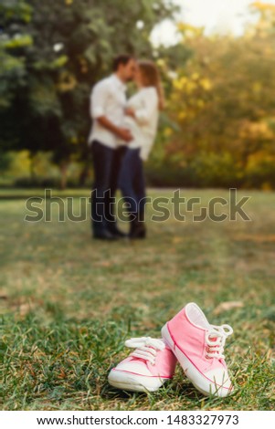 happy pregnant couple with little shoes for a daughter.