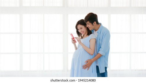 Happy Pregnant Couple Use Smart Phone At Home