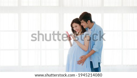 happy pregnant couple use smart phone at home