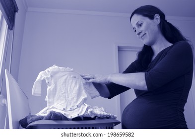 Happy Pregnant Housewife Woman Doing Housework, Washing Newborn Baby Clothes, During Pregnancy.Concept Photo Of Pregnancy, Pregnant Woman Lifestyle And Health Care. Copyspace (BW)