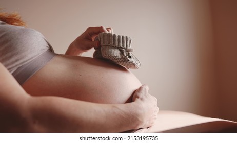 happy pregnant woman. booties baby shoes on the belly of a pregnant woman. pregnancy health procreation concept. close-up belly of a pregnant woman. woman lifestyle waiting for a newborn baby