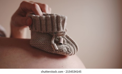 happy pregnant woman. booties baby shoes on the belly of a pregnant woman. pregnancy health procreation concept. close-up belly of a pregnant lifestyle woman. woman waiting for a newborn baby