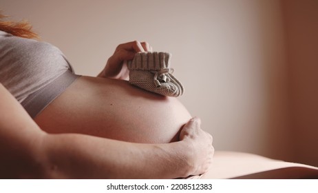 happy pregnant woman. booties baby shoes on the belly of a pregnant woman. pregnancy health procreation concept. close-up belly of a pregnant woman. woman lifestyle waiting for a newborn baby - Powered by Shutterstock