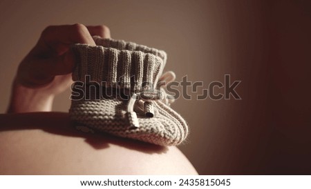 happy pregnant woman. booties baby shoes on the belly of a pregnant woman. pregnancy health lifestyle procreation concept. close-up belly of a pregnant woman. woman waiting for a newborn baby