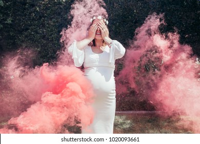 Happy Pregnant Woman Covering Her Face With Smoke Grenade Outdoors. Gender Reveal Party.