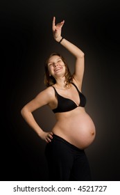 Happy Pregnant Woman Dancing Against Black Background