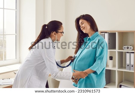 Happy pregnant woman has appointment with doctor at clinic. Female gynaecologist OB GYN medic specialist with stethoscope listens to baby's heartbeat in mother's belly. Pregnancy, health care concept