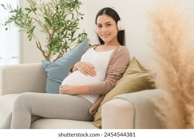 Happy pregnant woman with headphones listening to mozart music and lying on sofa, pregnancy concept - Powered by Shutterstock