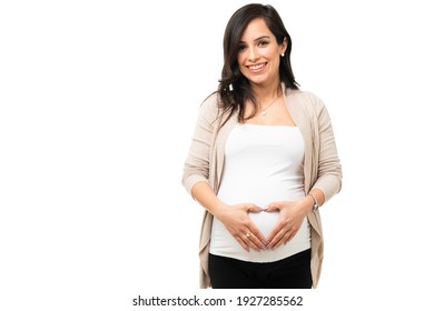 Happy pregnant woman in her 30s making a love heart sign in her round belly. Attractive caucasian woman feeling excited for her new baby