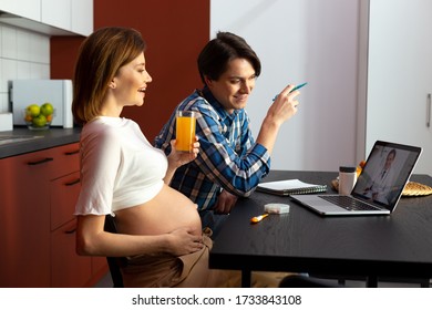 Happy Pregnant Woman And Her Caring Husband Are Having Online Appointment With Doctor At Home