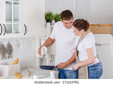 Happy pregnant woman and her husband cook food in the kitchen. - Powered by Shutterstock