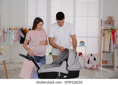 Happy Pregnant Woman With Her Husband Choosing Baby Stroller In Store. Shopping Concept