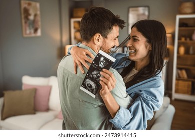 Happy pregnant woman with hug her husband and watch ultrasound photo of baby - Powered by Shutterstock