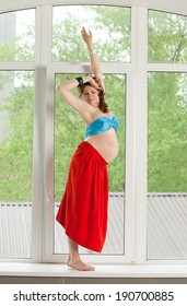 Happy pregnant woman in long skirt and bright bra