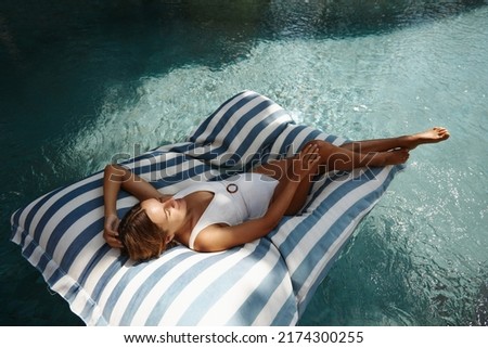 Happy pregnant woman in a luxury five star spa resort in the pool on an inflatable pillow