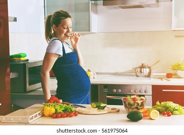 happy pregnant woman on kitchen making healthy salad
