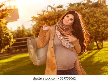 Happy pregnant woman with shopping bag in sunny autumn day on the backyard, preparing to baby birth, enjoying last days of pregnancy