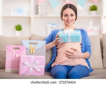 Happy pregnant woman is sitting with presents at a baby shower.