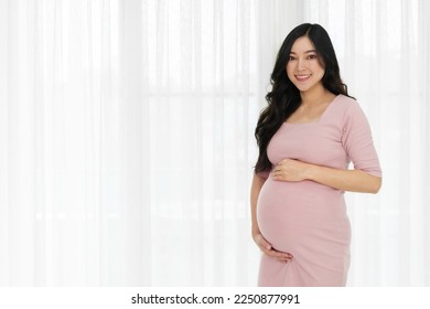 happy pregnant woman stroking her belly on window background - Powered by Shutterstock