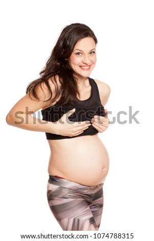 Happy pregnant woman touching her breasts on white background