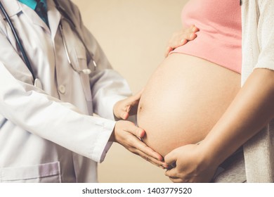 Happy pregnant woman visit gynecologist doctor at hospital or medical clinic for pregnancy consultant. Doctor examine pregnant belly for baby and mother healthcare check up. Gynecology concept. - Powered by Shutterstock