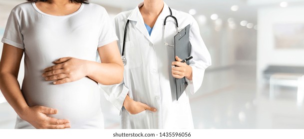 Happy Pregnant Woman Visit Gynecologist Doctor At Hospital Or Medical Clinic For Pregnancy Consultant. Doctor Examine Pregnant Belly For Baby And Mother Healthcare Check Up. Gynecology Concept.