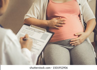 Happy Pregnant Woman Visit Gynecologist Doctor At Hospital Or Medical Clinic For Pregnancy Consultant. Doctor Examine Pregnant Belly For Baby And Mother Healthcare Check Up. Gynecology Concept.