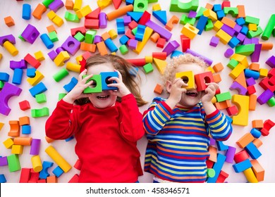 Happy preschool age children play with colorful plastic toy blocks. Creative kindergarten kids build a block tower. Educational toys for toddler or baby. Top view from above. - Shutterstock ID 458346571