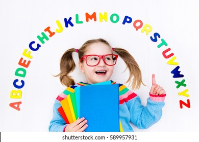 Happy Preschool Child Learning To Read And Write Playing With Colorful Roman Alphabet Letters. Educational Abc Toys And Books For Kids. School Student Doing Homework. Kid Reading In Kindergarten.