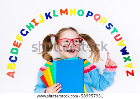 Happy preschool child learning to read and write playing with colorful roman alphabet letters. Educational abc toys and books for kids. School student doing homework. Kid reading in kindergarten.