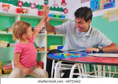 Happy Preschool Teacher And Child Giving High-five