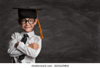 Happy Preschooler Boy in Eyeglasses and Graduation Hat over Blackboard with Copy Space. Happy Little Kid like Student in Smart Casual White Shirt Black Tie. Clever Child in Master Cap