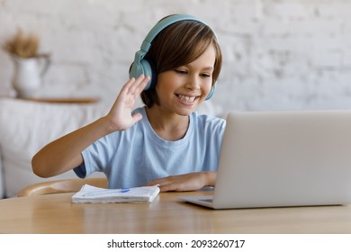 Happy preteen adorable child boy in wireless headphones waving hand looking at laptop screen, starting video call class online with teacher, enjoying studying on internet courses, e-learning concept. - Shutterstock ID 2093260717