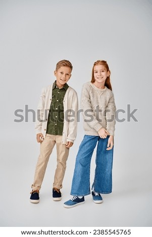 happy preteen friends in casual winter clothes on gray backdrop, smiling at camera, fashion concept