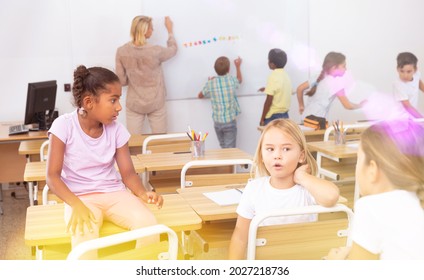 Happy preteen schoolchildren communicating during recess between lessons in classroom - Shutterstock ID 2027218736