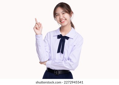 Happy pretty Asian student girl in school uniform pointing finger up isolated on white background.