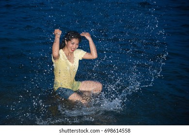Happy pretty Asian woman open arms having fun in the sea playing at night.