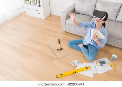 Happy Pretty Female Designer Using Virtual Reality Technology Device Watching House Construction Simulation Video And Touching Screen Choosing Design Color. High Angle View Photo.